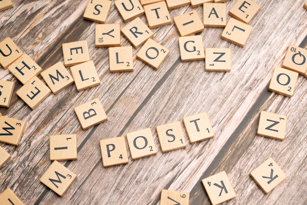 Wooden scrabble tiles scattered with the word POST on a rustic wooden surface.